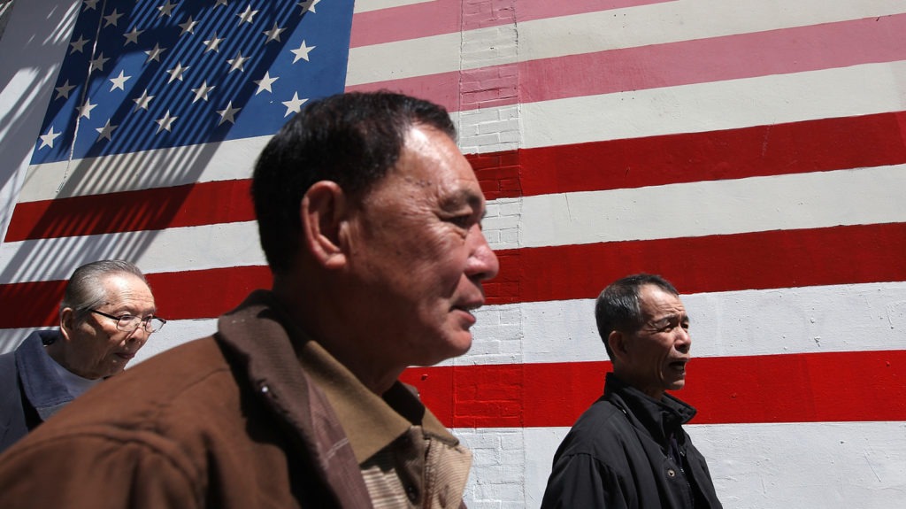 Asian immigrants standing in front of the American flag